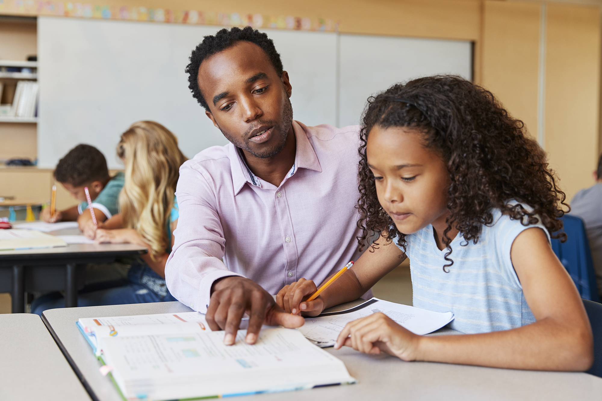 image of teacher looking at a text book with a student