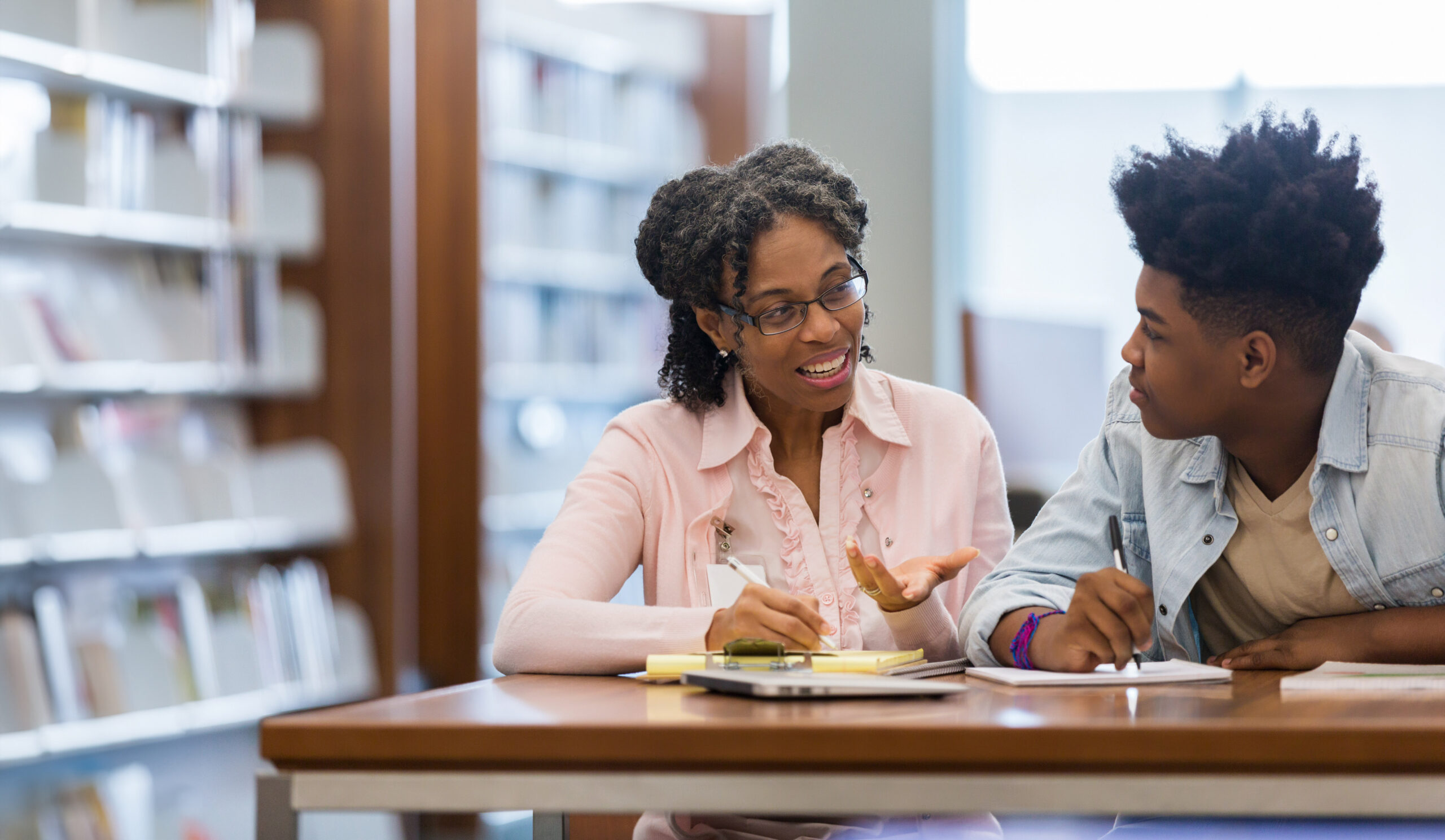 a teacher talking to a student in a library